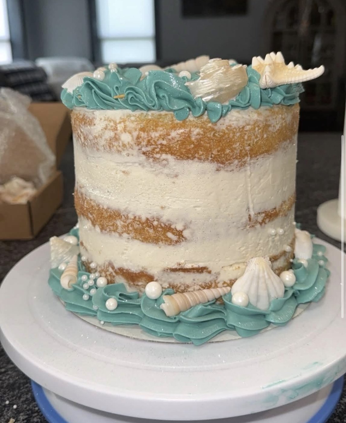 Custom naked layer cake with teal buttercream and sugar seashells